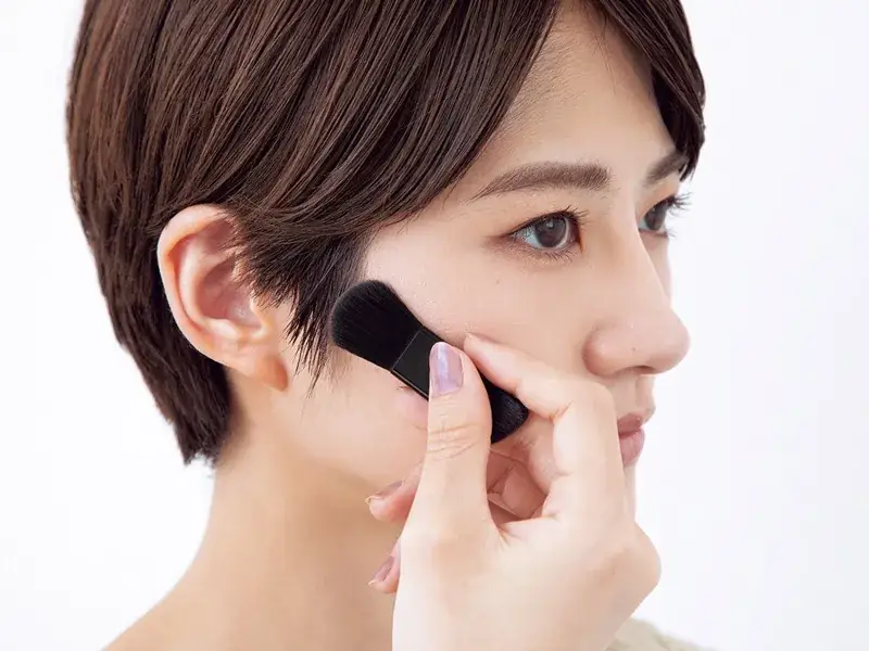 若月佑美さん ブラシでフェイスカラーを頬の横にのせる様子