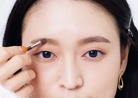 パウダーをブラシで眉に塗布している写真